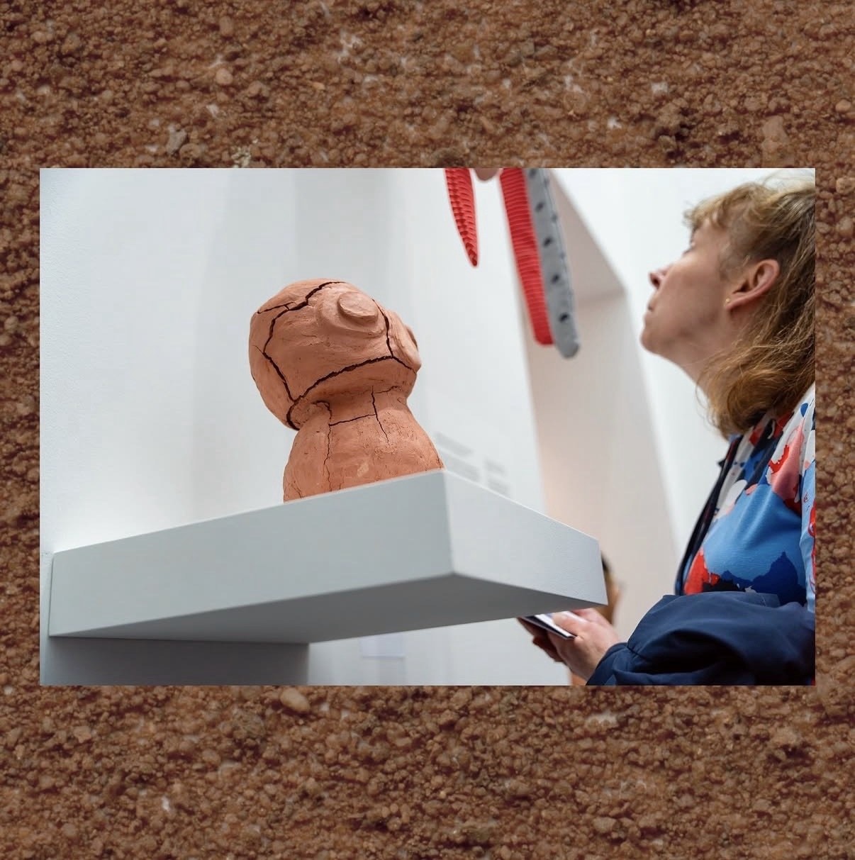 A visitor looking up past Shoco, a small cracked clay figure on a white shelf