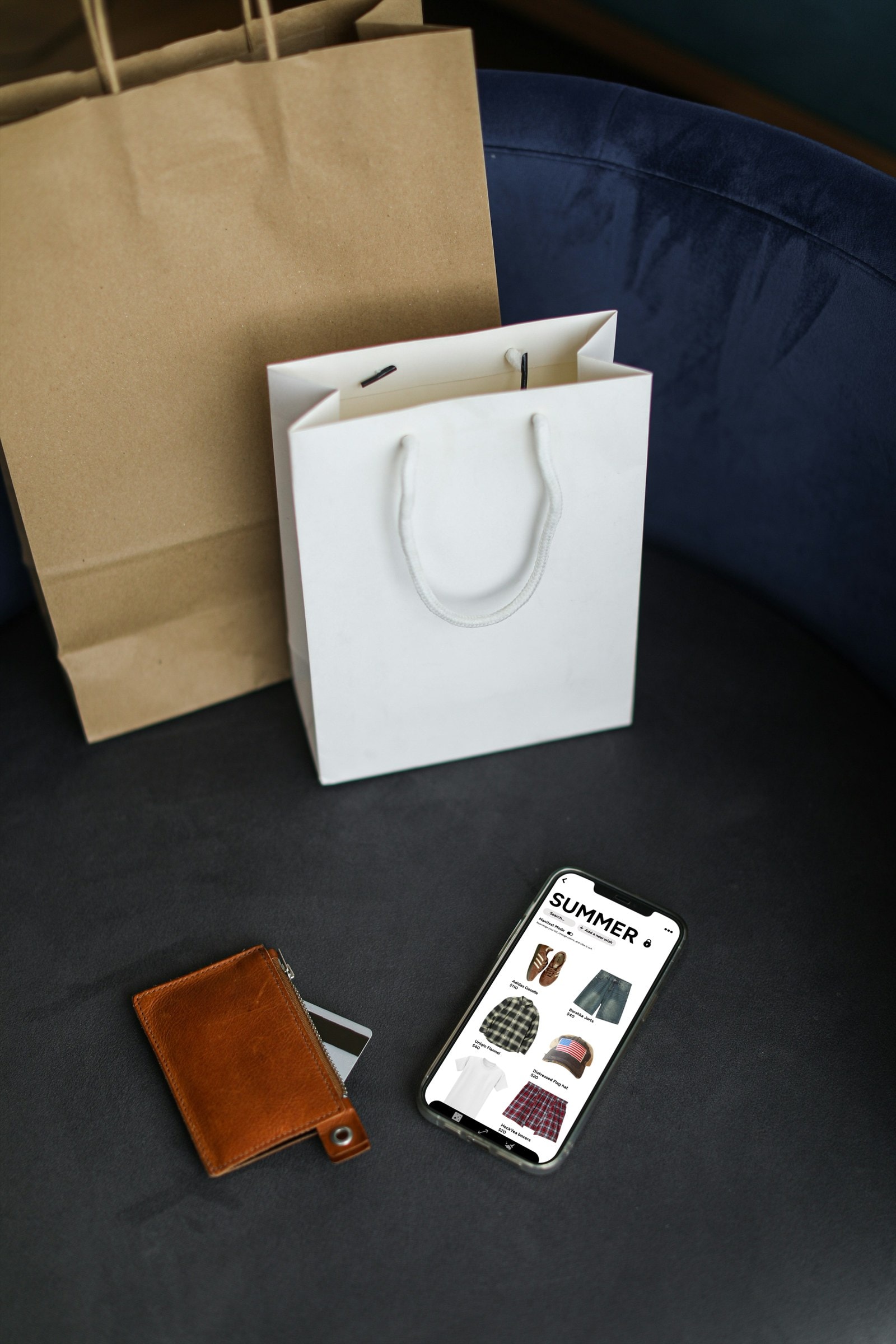 Shopping bags, a wallet and a phone showing a Summer wishlist