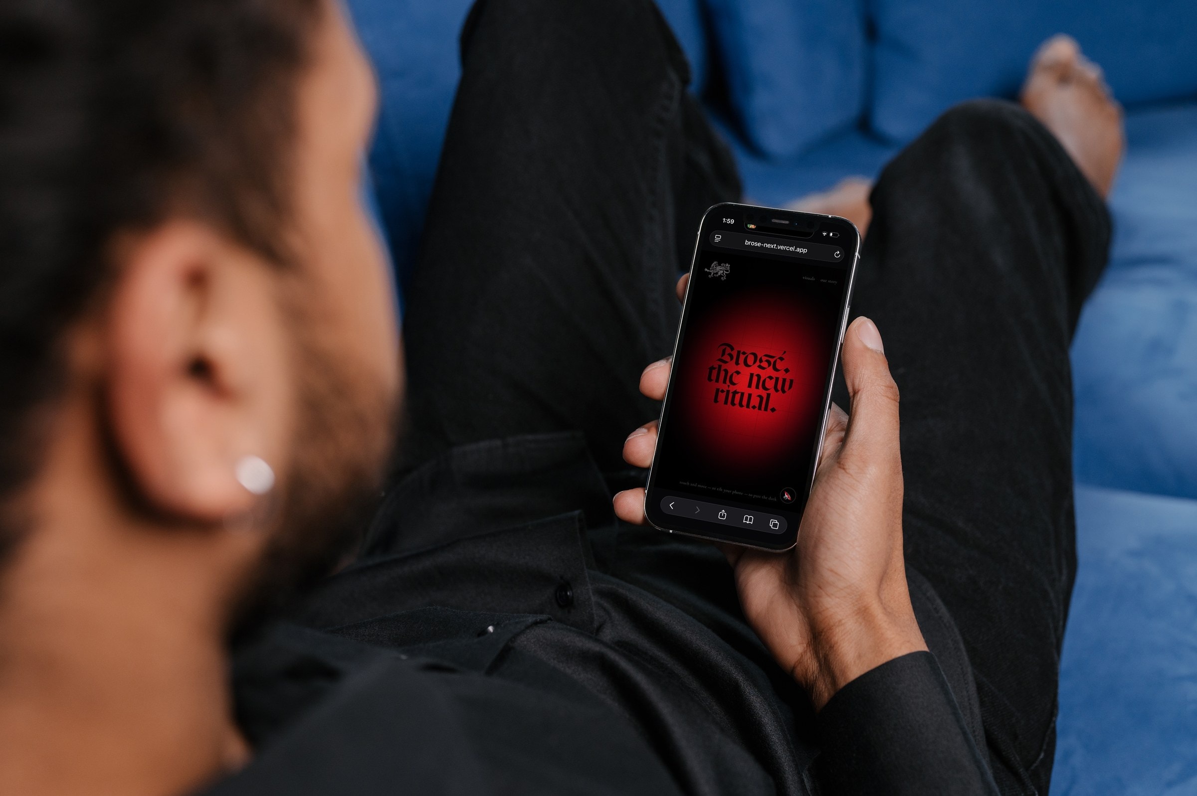Man on a blue sofa viewing the Brosé website on his phone