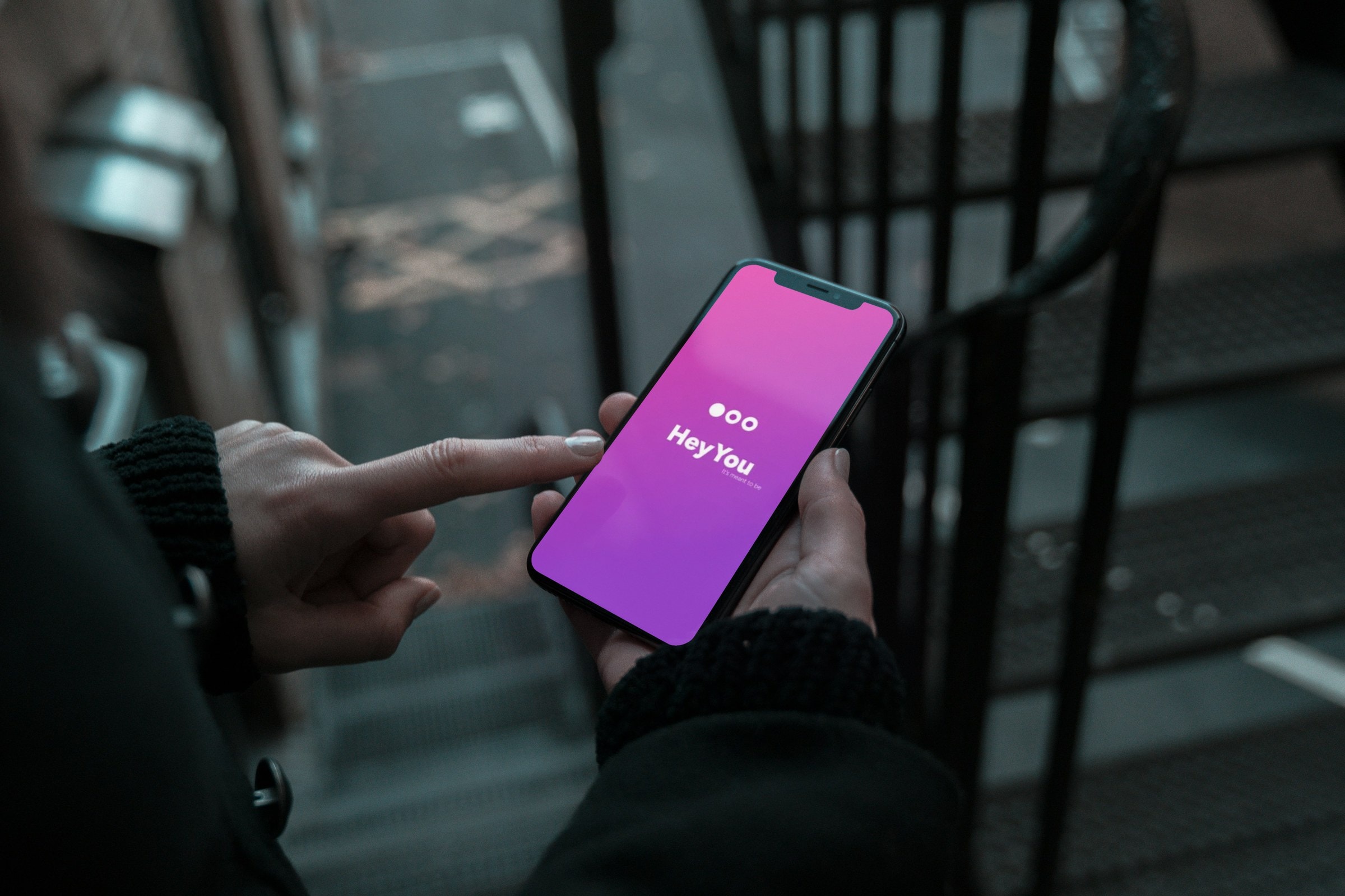 Finger tapping the pink Hey You splash screen on a phone