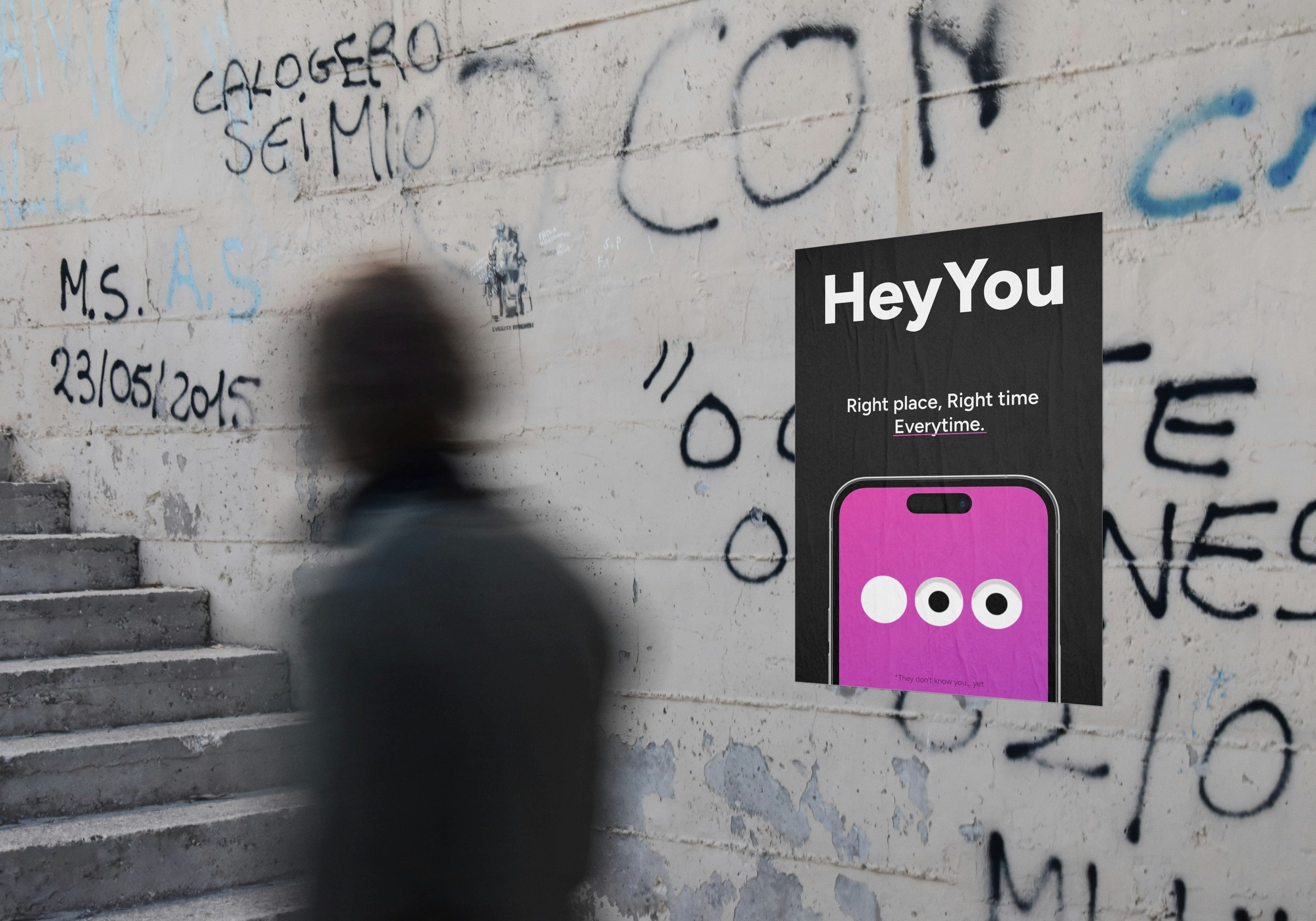 Blurred passer-by in front of a Hey You poster on a graffiti wall