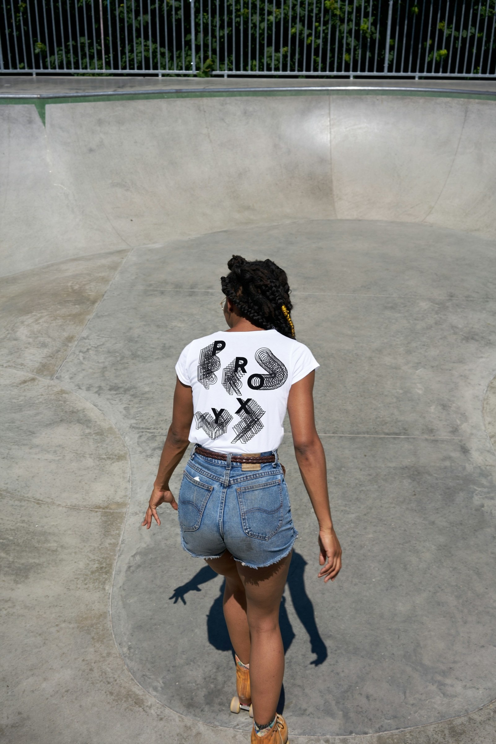 Roller skater in a skate bowl wearing the white Proxy shirt, back print visible